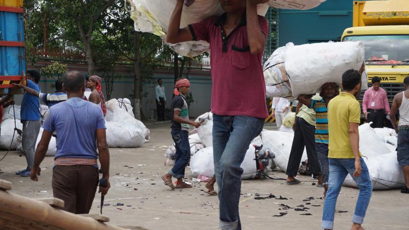 Arbeiter entladen Stoffmühl in einer Fabrik in Bangladesch.